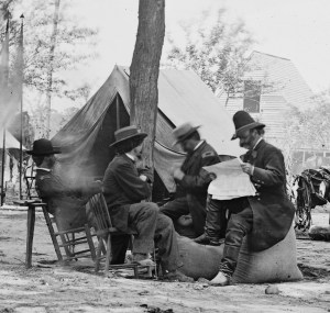 Ambrose Burnside (reading paper) and staff at Cold Harbor, June 11 or 12, 1864. That's photographer Matthew Brady in the straw hat (Library of Congress).